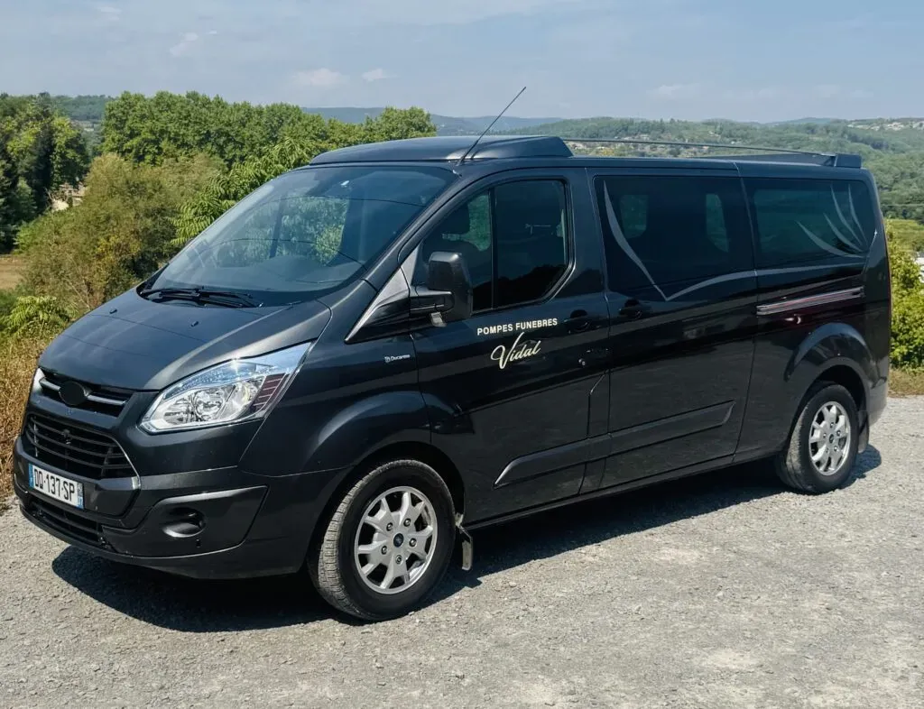 Corbillard ou véhicule de transport funéraire noir garé en extérieur.