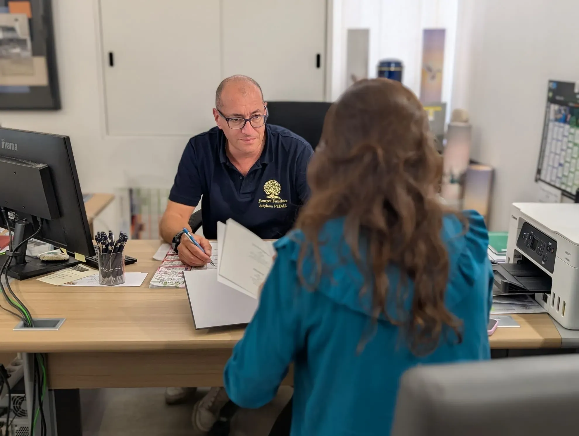 Conseiller funéraire au bureau en train d'échanger avec une cliente lors d'un entretien.