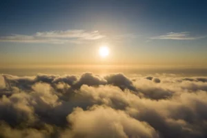 Vue aérienne au-dessus d'une mer de nuages éclairée par un soleil couchant